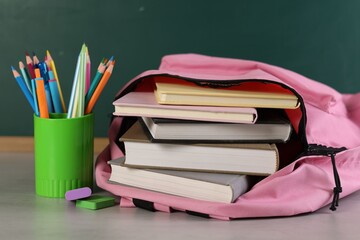 Backpack with books and stationery on white desk against chalkboard © New Africa