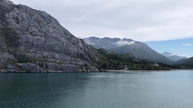Majestic Rocky Mountain Cliff Rising Steeply from Calm Alaskan Ocean Inlet