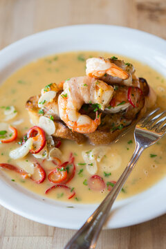 Crostini with white shrimp, garlic, chile and pancetta on a plate with fork over the plate.