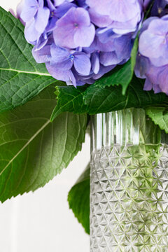 Purple hydrangea bouquet in textured glass vase