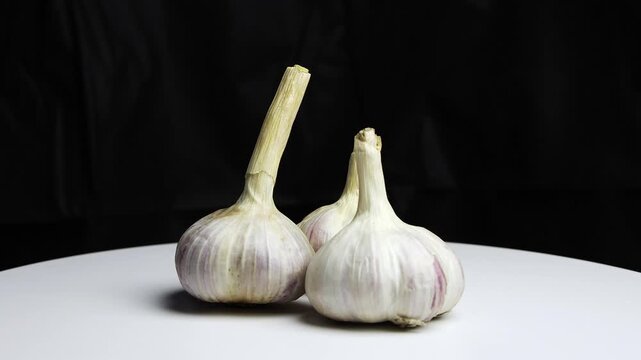 Three Fresh Garlic Bulbs with Stems on Light Background