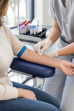 Nurse preparing patient arm for blood test in clinic with collection tubes on medical tray