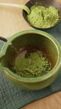 Pouring hot water into ceramic bowl with bright green matcha powder. Healthy detox superfood beverage preparation of Japanese green tea or matcha latte.