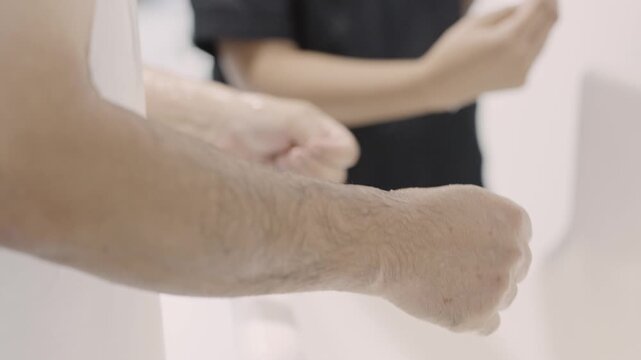 Medical professional washing and sanitizing hands carefully at clinic sink before surgery