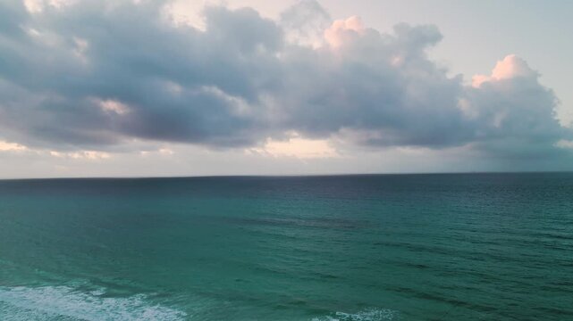 Calm turquoise sea meeting the shore under a cloudy dusk sky