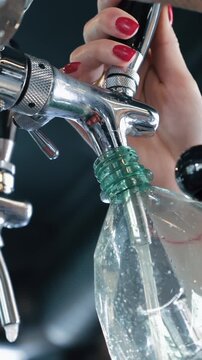 Beer filling glass bottle from tap close up, craft brewery bottling process and beverage production concept with selective focus, Vertical Video.