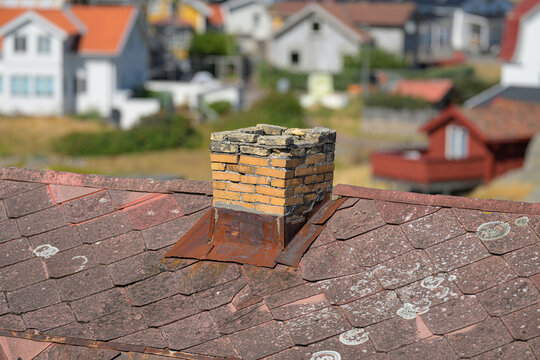 Weathered brick chimney rising from old coastal house roof.