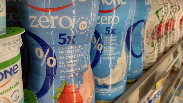 ITABIRA, MINAS GERAIS, BRAZIL - SEPTEMBER 15, 2026: Bottles of Danone zero sugar strawberry drinkable yogurt highlighting 0% added sugar and lactose free claims on a refrigerated supermarket shelf.