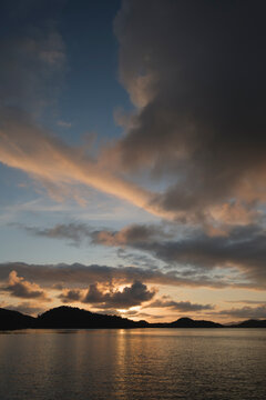Coastline by fjord under clouds during sunset