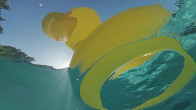 Yellow duck pool float on calm surface shot from below water line