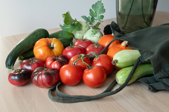 Woven green shopping bag with various fall vegetables on table, home food shopping