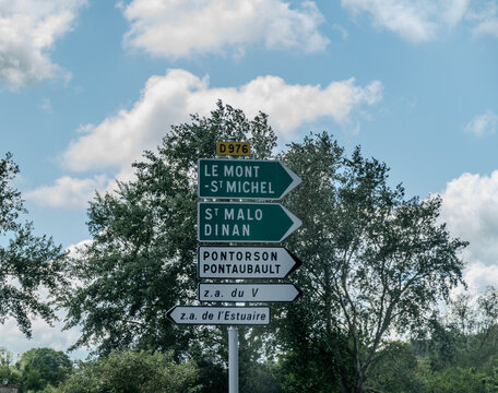Road signs and directional markers displaying Breton and Normandy city and village names along scenic driving routes through the Brittany countryside, France