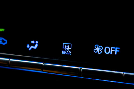 Close-up of car climate control panel showing blue illuminated rear defroster and fan off symbols