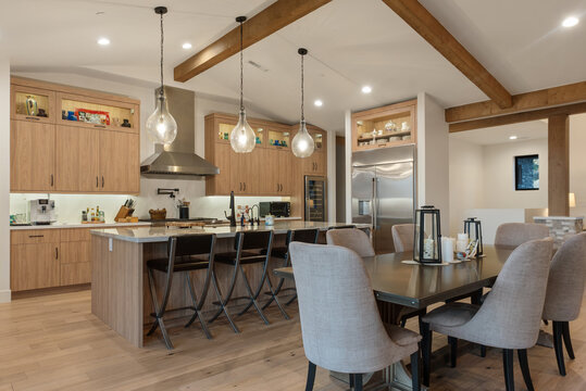 Spacious kitchen interior with wooden beams pendant lights, meal seating, stainless steel appliances