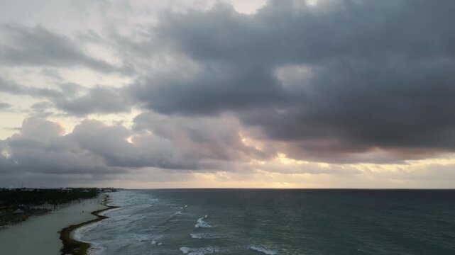 Dramatic dusk clouds drifting over a quiet coastline aerial view