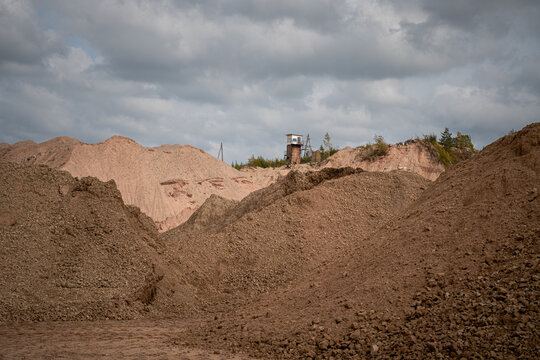 Large gravel and sand stockpiles at an open pit quarry under dramatic cloudy sky