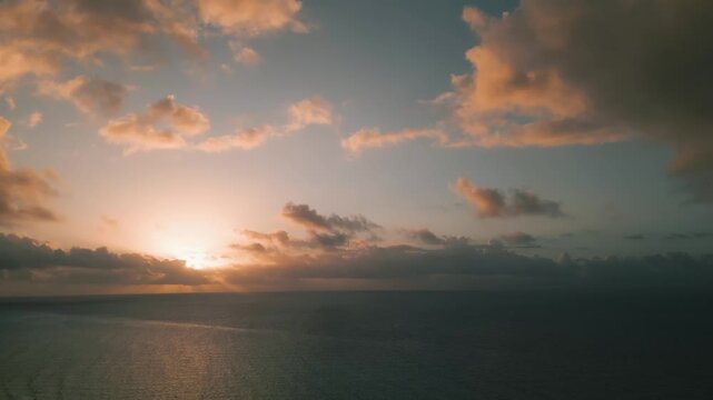 Golden clouds drifting above a calm ocean at sunset