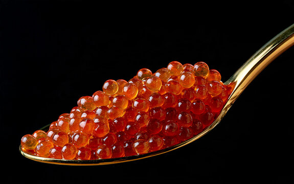 Orange salmon roe is piled on a golden spoon against a black background.