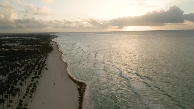 Aerial sweep along a glowing coastline at golden dusk