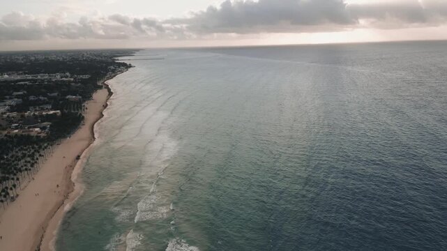 Drone flight tracing a curving coastline dotted with coastal towns
