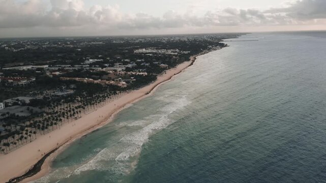 Drone view of a curving coastline meeting turquoise ocean at dusk