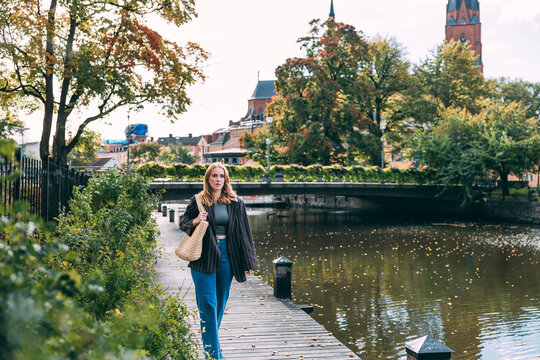 Young woman walking by river in Uppsala, Sweden