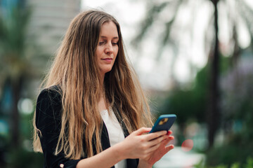 Young woman concentrating on mobile phone screen, using digital technology for communication and...