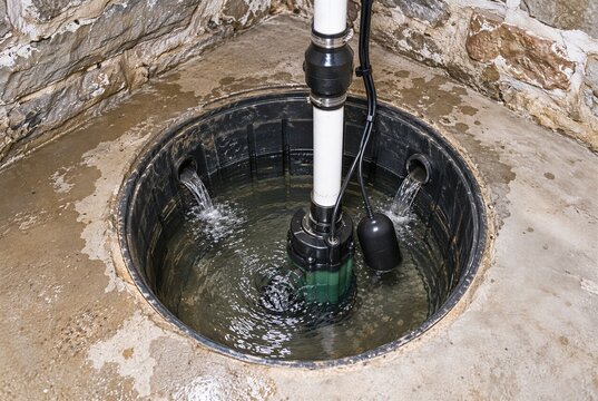 Residential sump pump operating in a basement drainage pit with groundwater flowing from perimeter drain inlets showing flood prevention drainage waterproofing and home protection concept