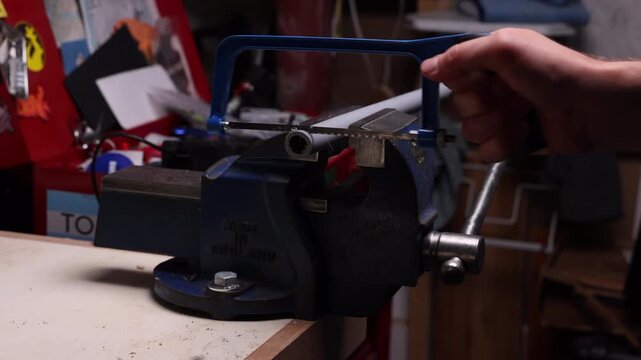 Man sawing plastic pipe with hack saw in home work shop