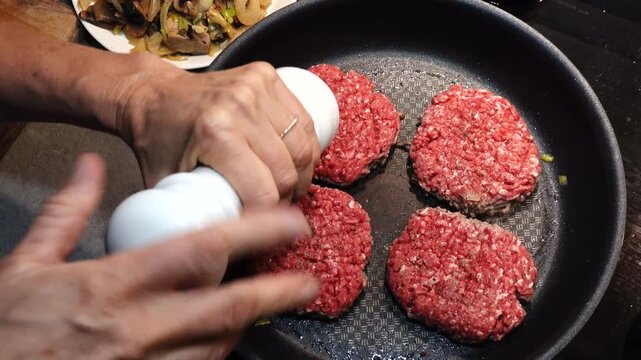 Stockholm, Sweden A cook in a residential kitchen fries homemade hamburger patties in a frying pan. 