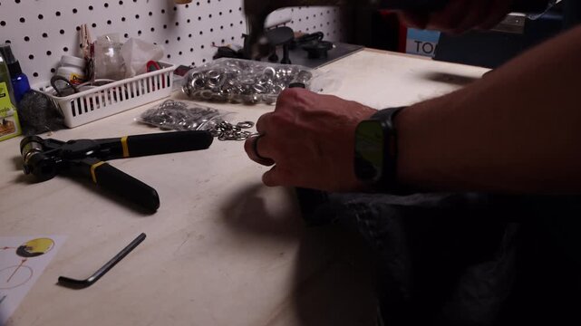 Hammer clanking down on hole punch as man cuts hole in fabric