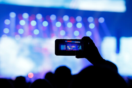 Smartphone screen recording a live music concert with blue lights