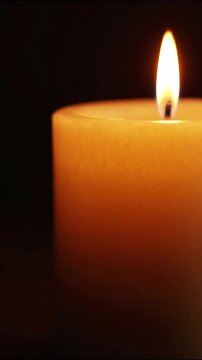Burning candle flame glowing in darkness, creating a warm atmosphere for meditation