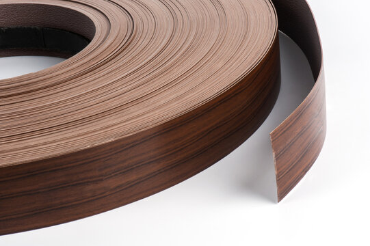 Close-up studio photograph of a large roll of flexible wood-grain edge banding with an unrolled strip, isolated on a white background. 
