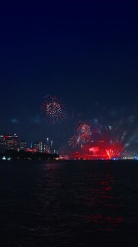 Dark sky colored by the splashes of gorgeous fireworks at night. Harbor of New York City during the Independence Day celebration. Vertical video.