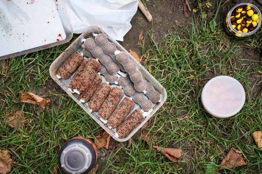 Top view of prepared PVA sticks and mesh bags with bait pellets for carp fishing. Flat lay of groundbait containers, boilies and liquid attractant on a grassy ground.
