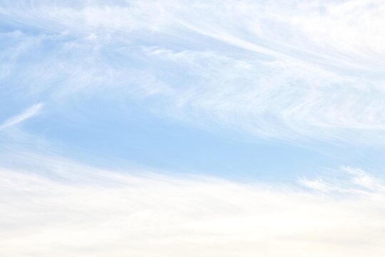 Soft white cirrostratus and wispy cirrus clouds on pale blue sky background