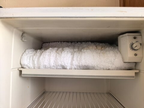 A freezer compartment covered in thick frost and ice, rarely cleaned and poorly maintained.