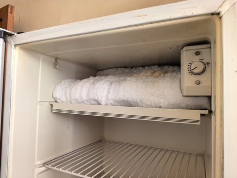 A freezer compartment covered in thick frost and ice, rarely cleaned and poorly maintained.