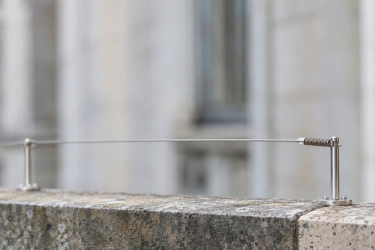 Spring tensioned bird deterrent wire on a stone parapet