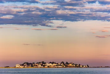 Little Nahant Island viewed from Revere Beach across Black Rock Channel, Massachusetts, at sunset, with the island silhouetted against the golden evening sky and calm coastal waters. © mandritoiu