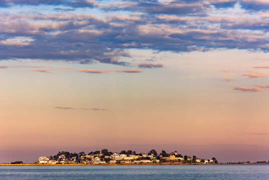 Little Nahant Island viewed from Revere Beach across Black Rock Channel, Massachusetts, at sunset, with the island silhouetted against the golden evening sky and calm coastal waters.