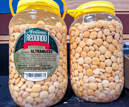 Denia, Spain - October 10, 2025. Large plastic containers of Aceitunas Redondo pickled Altramuces lupine beans in a Spanish store display