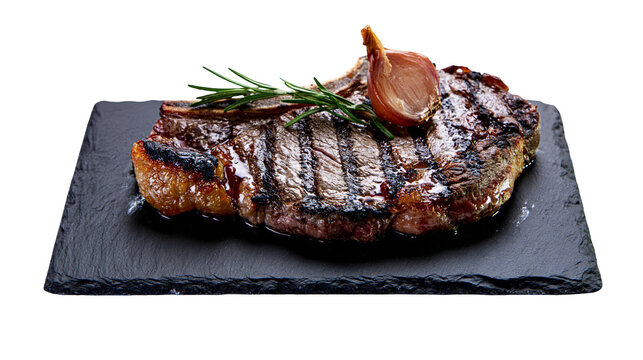 Isolated delicious grilled steak with rosemary and garlic on black slate serving board