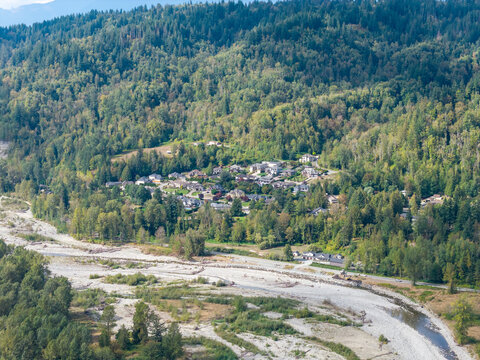 Suburban Homes in Chilliwack BC Canada Nestled Below Forested Hillside Along Riverbank