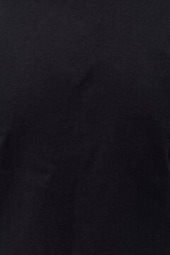 Minimalist background: close-up shot of a dark black cotton-blend jersey knit fabric with a subtle textile texture and slight natural folds. Ideal for product mockups and fashion.