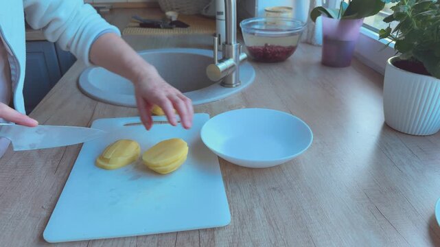  Potato sliced into wedges for frying or baking, preparation stage for crispy homemade dish.