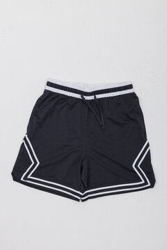 Flat lay shot of black athletic mesh basketball shorts with white geometric stripes and drawstring, isolated on a plain background. Perfect mockup template for sportswear branding.