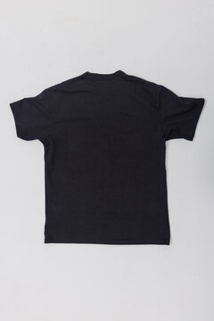 Flat lay back view of a plain black cotton t-shirt isolated on a light background. Perfect blank mockup template for apparel branding, back print design presentation, or online store catalog.