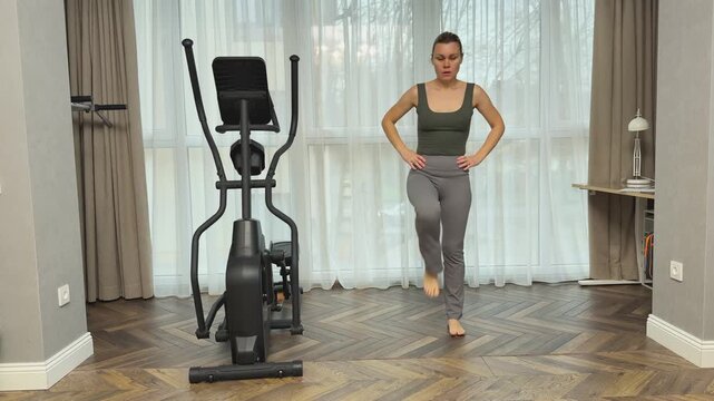  Woman performs marching steps lifting knees high while standing in living room. Simple home cardio routine for warmup and daily activity.